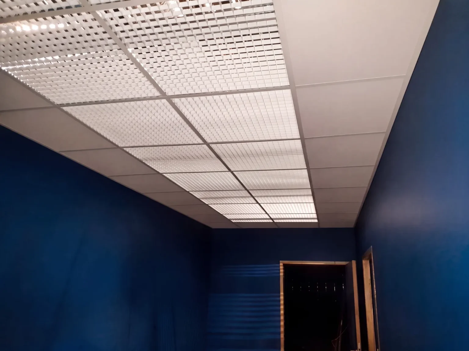 Plafond d'un couloir bleu avec un système d'éclairage encastré et une porte ouverte