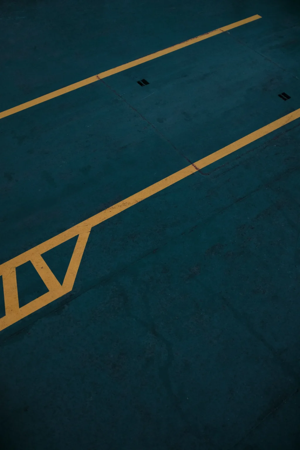 Lignes jaunes délimitant des zones sur un sol teinté de bleu profond, possiblement un terrain de jeu ou de sport.
