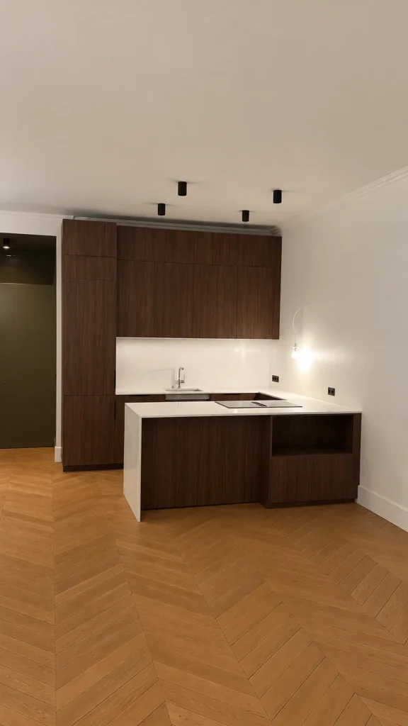 Cuisine moderne avec des armoires en bois foncé, un îlot central blanc, un plan de travail en marbre avec évier et plaque de cuisson intégrés.