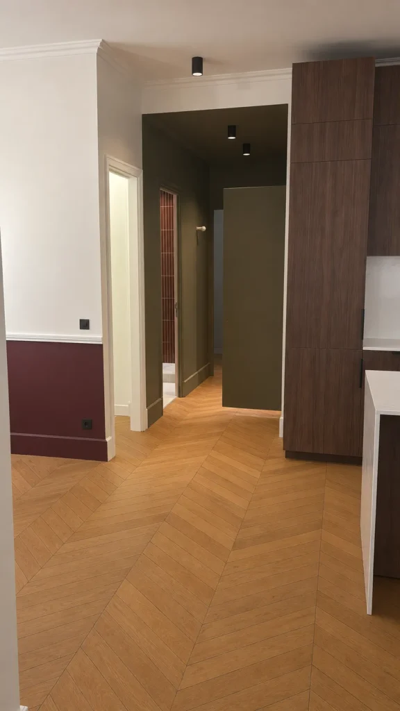 Parquet en chevrons dans un couloir moderne avec des murs aux couleurs contrastées et des portes sombres.